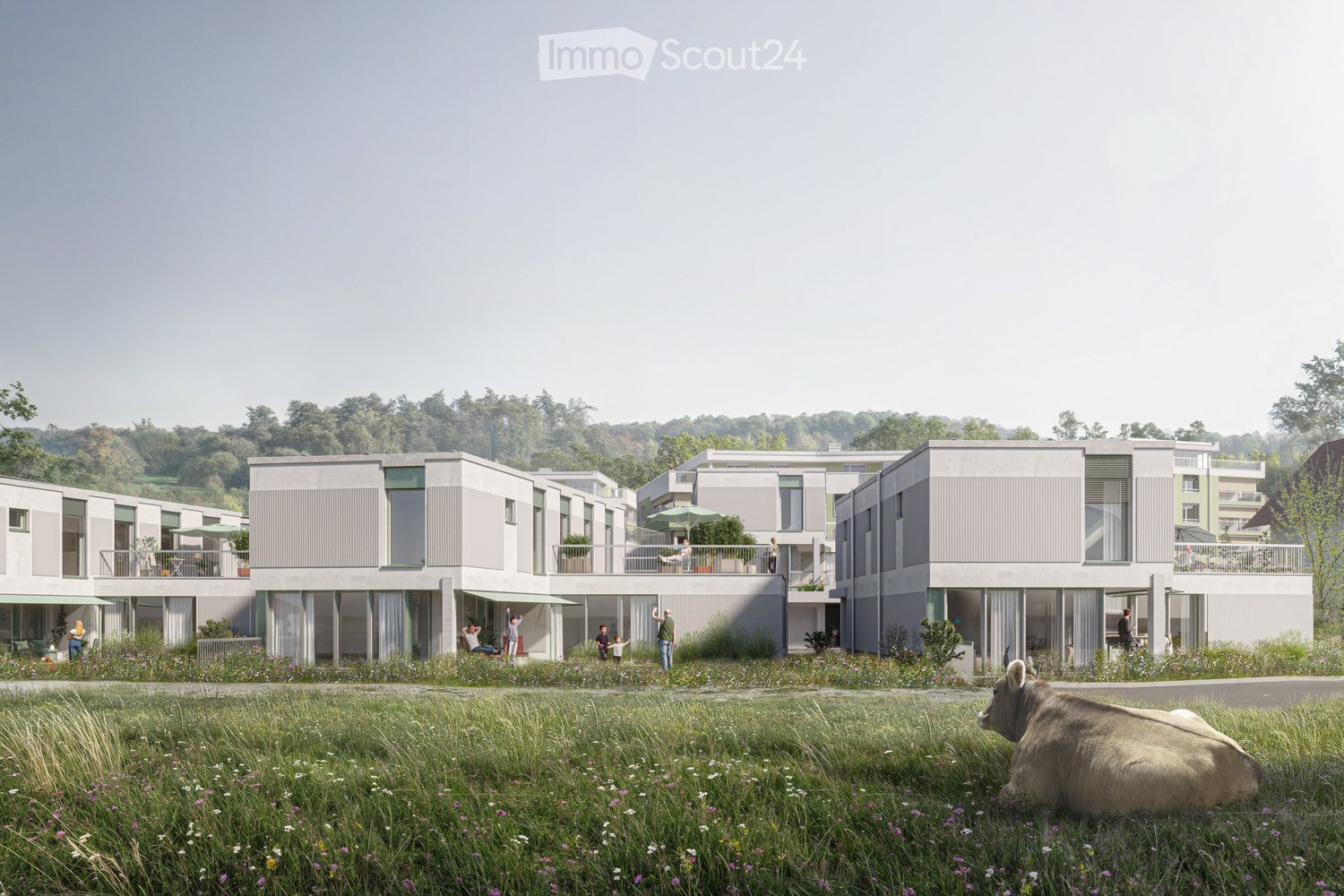 Modern housing complex with multiple floors, balconies, set in a green landscape with a cow in the foreground