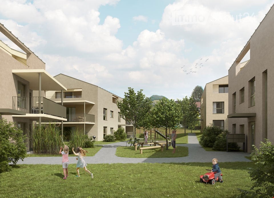 A complex of buildings with an outdoor area that includes benches, a slide, trees, and an area for children to play