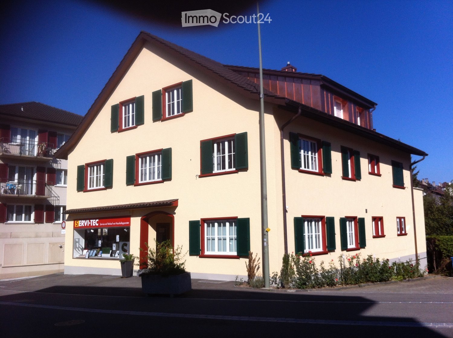 3 story house, yellow walls, green shutters, store at the front, red frame