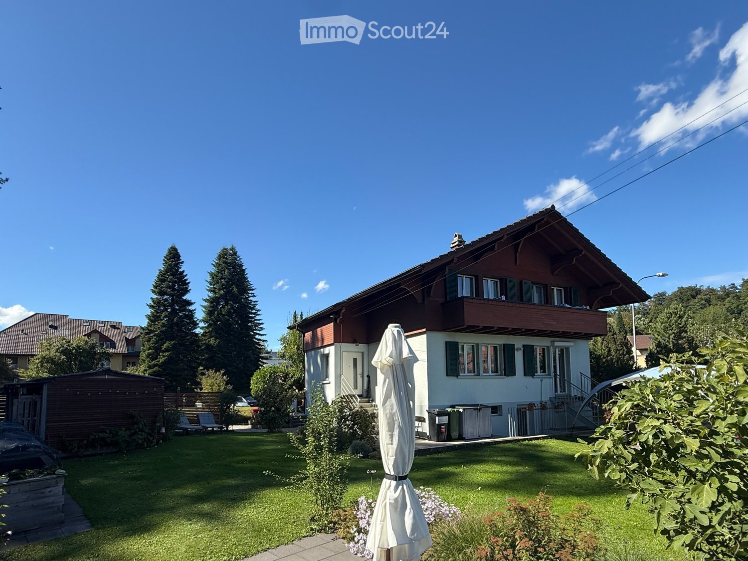 brown wooden house, white walls, balcony, lawn, garden, large trees, outdoor seating area