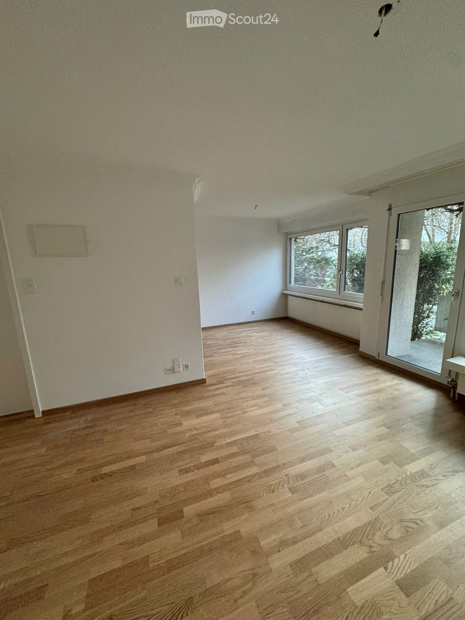 empty room, wooden floor, white walls, window with blinds, glass door leading to balcony