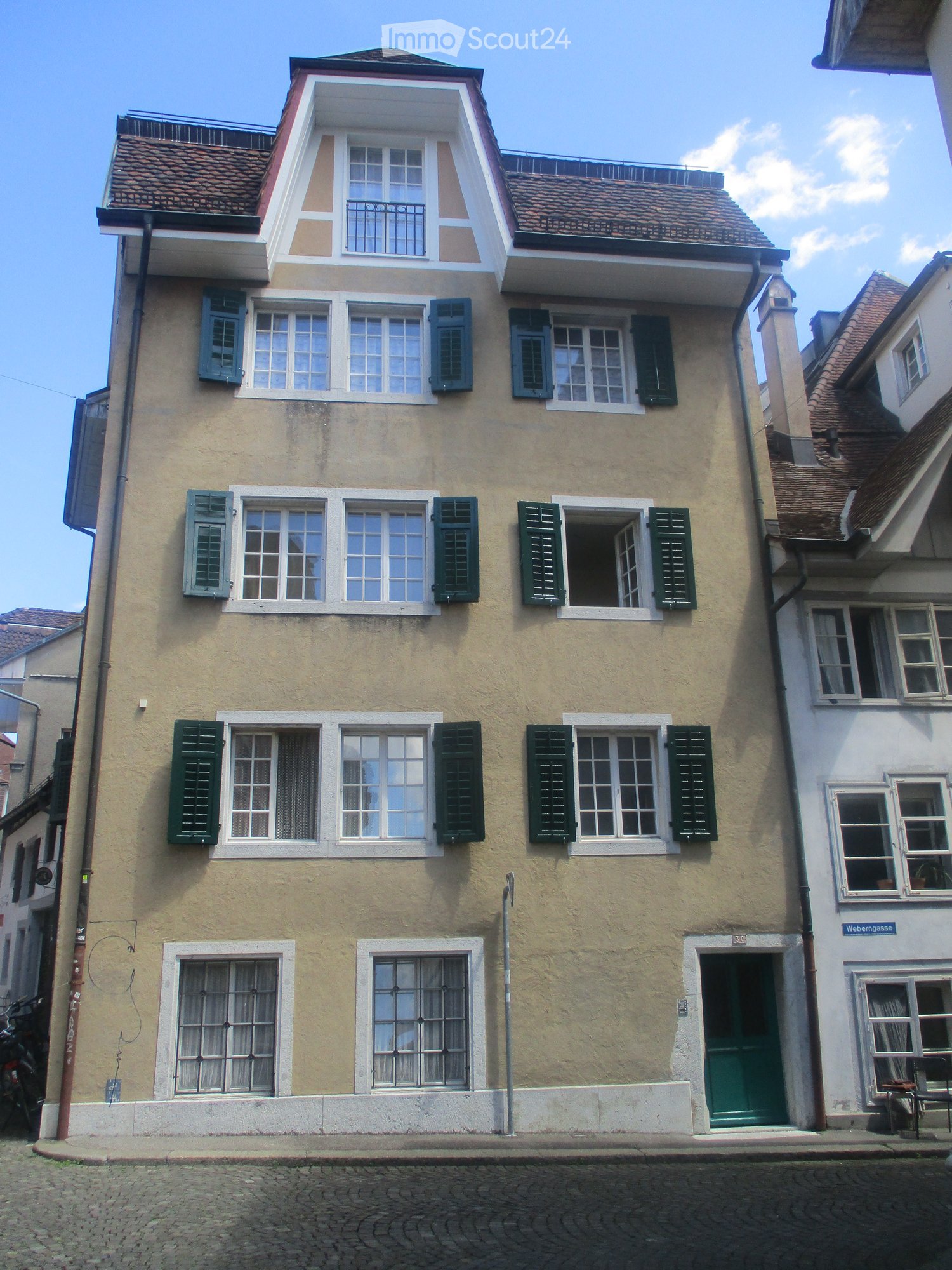 multi story building, many windows, green shutters, brown roof