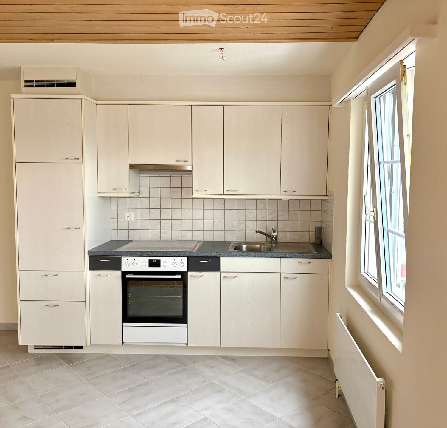 Modern kitchen with white cabinets, tile walls, stainless steel sink, electric stove and oven, tiled floor, window with daylight