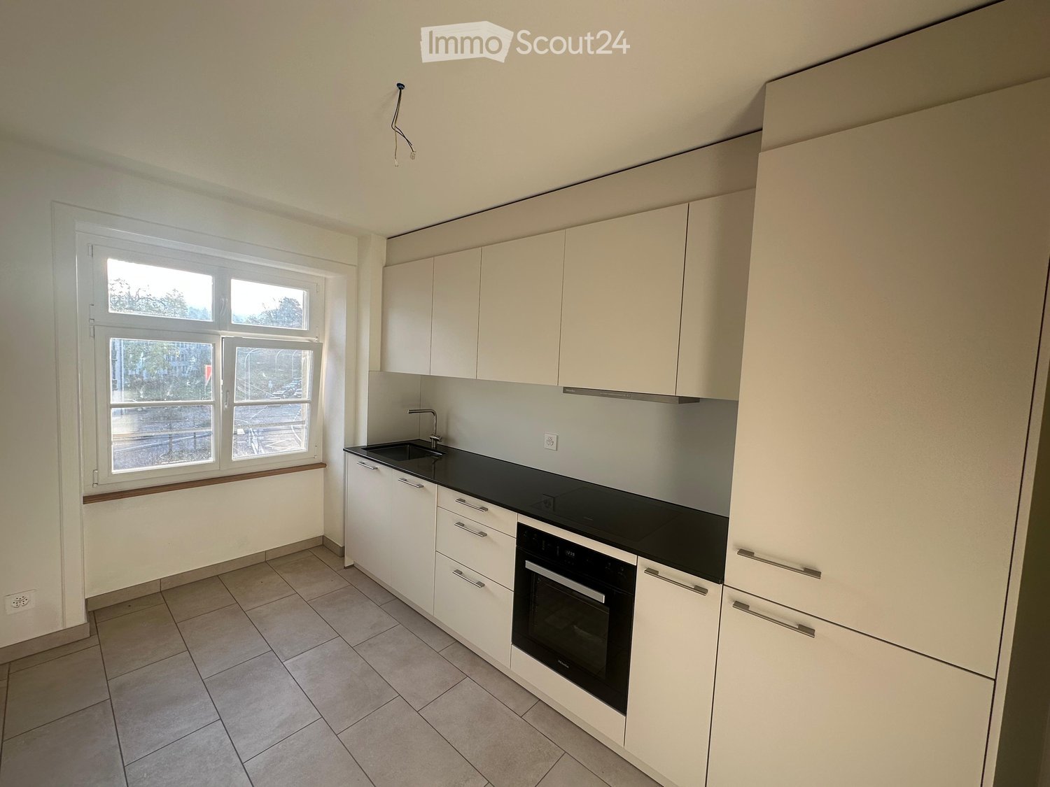 modern kitchen with white cabinets, black countertop, white sink, oven, underfloor heating