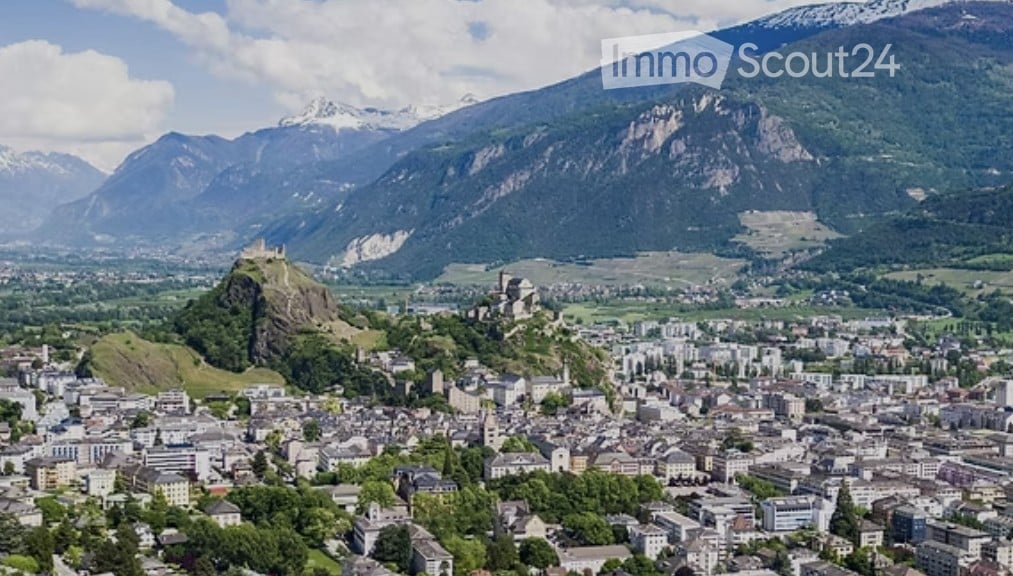 Aerial view of Sion, Switzerland, overlooking buildings, green hills, mountain range, castle on a hill