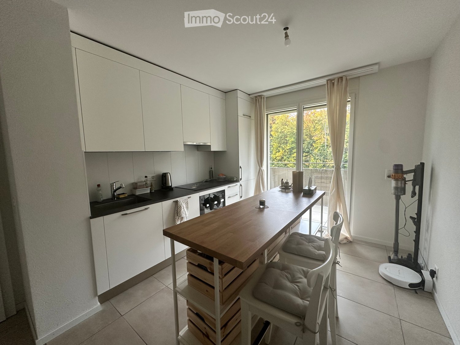 modern kitchen, white cabinets, wooden island, kitchen appliances, large windows, access to balcony