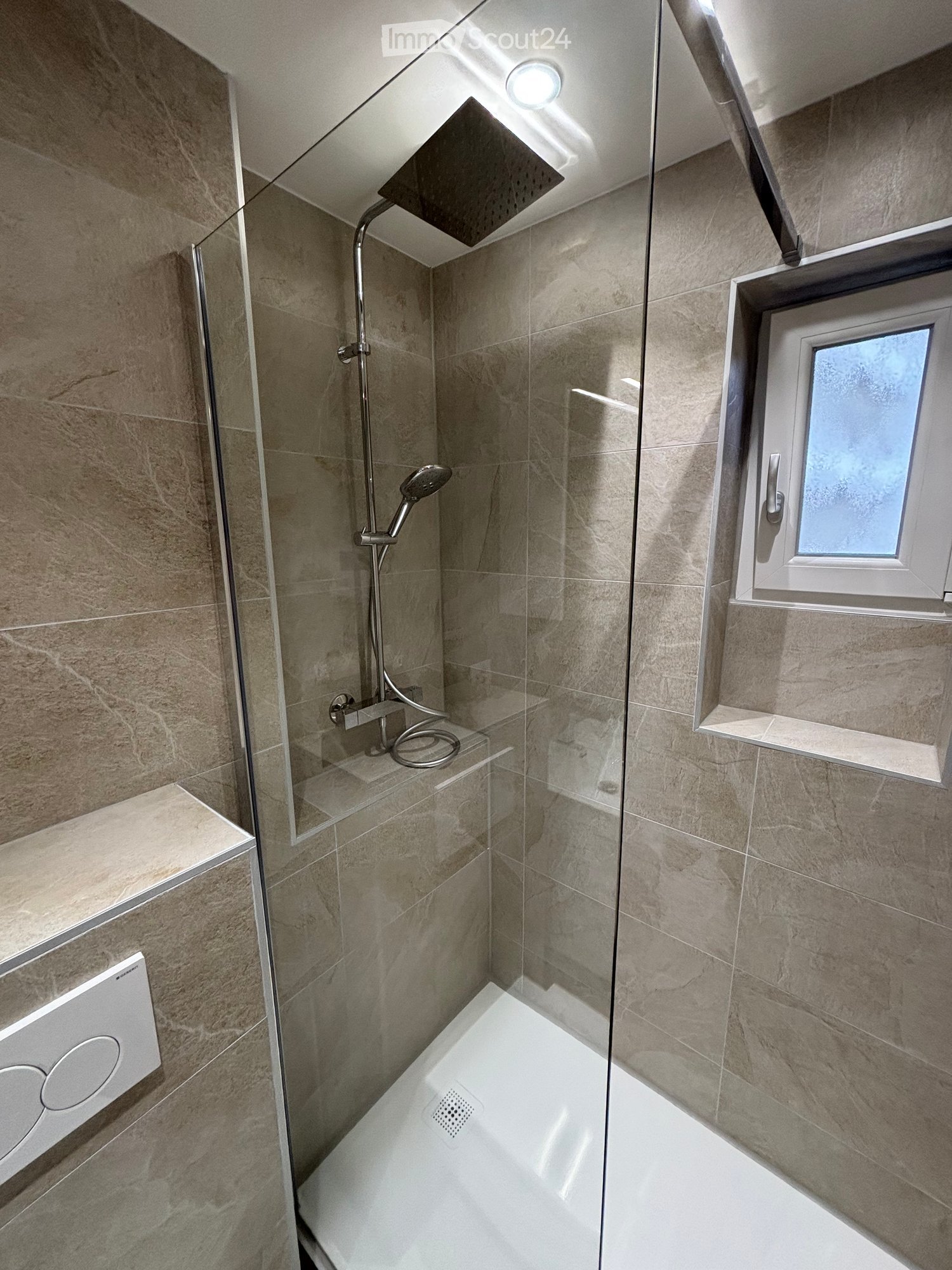 Shower enclosure, built-in shower head, tiled walls and floor, glass door, small window, and silver showerhead