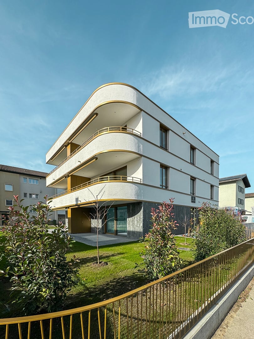 Modern 3-story building, white and yellow accents, glass windows, balconies, fence, green lawn