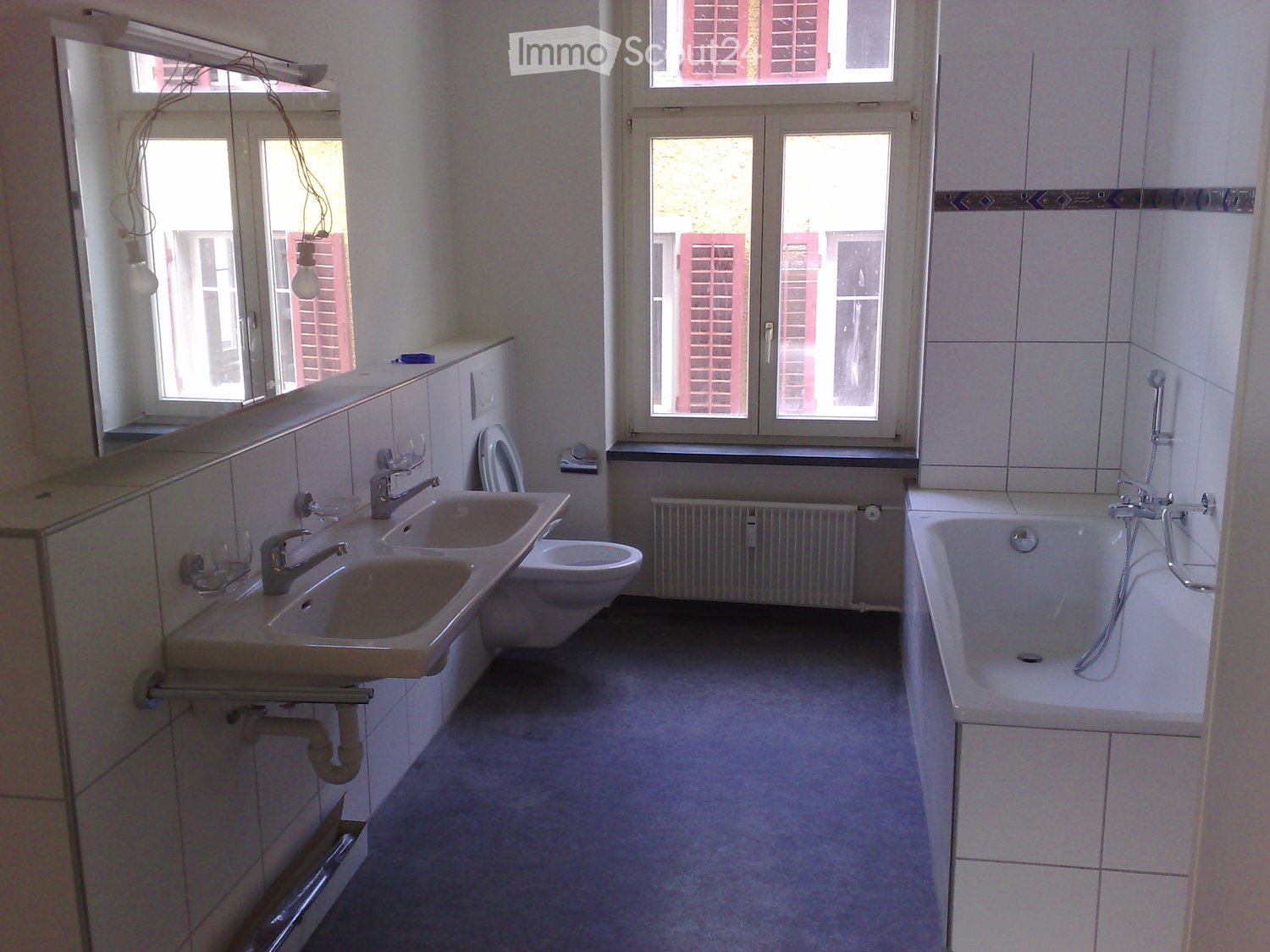 Bathroom with two sinks, toilet, bathtub, radiator, windows, tiled walls