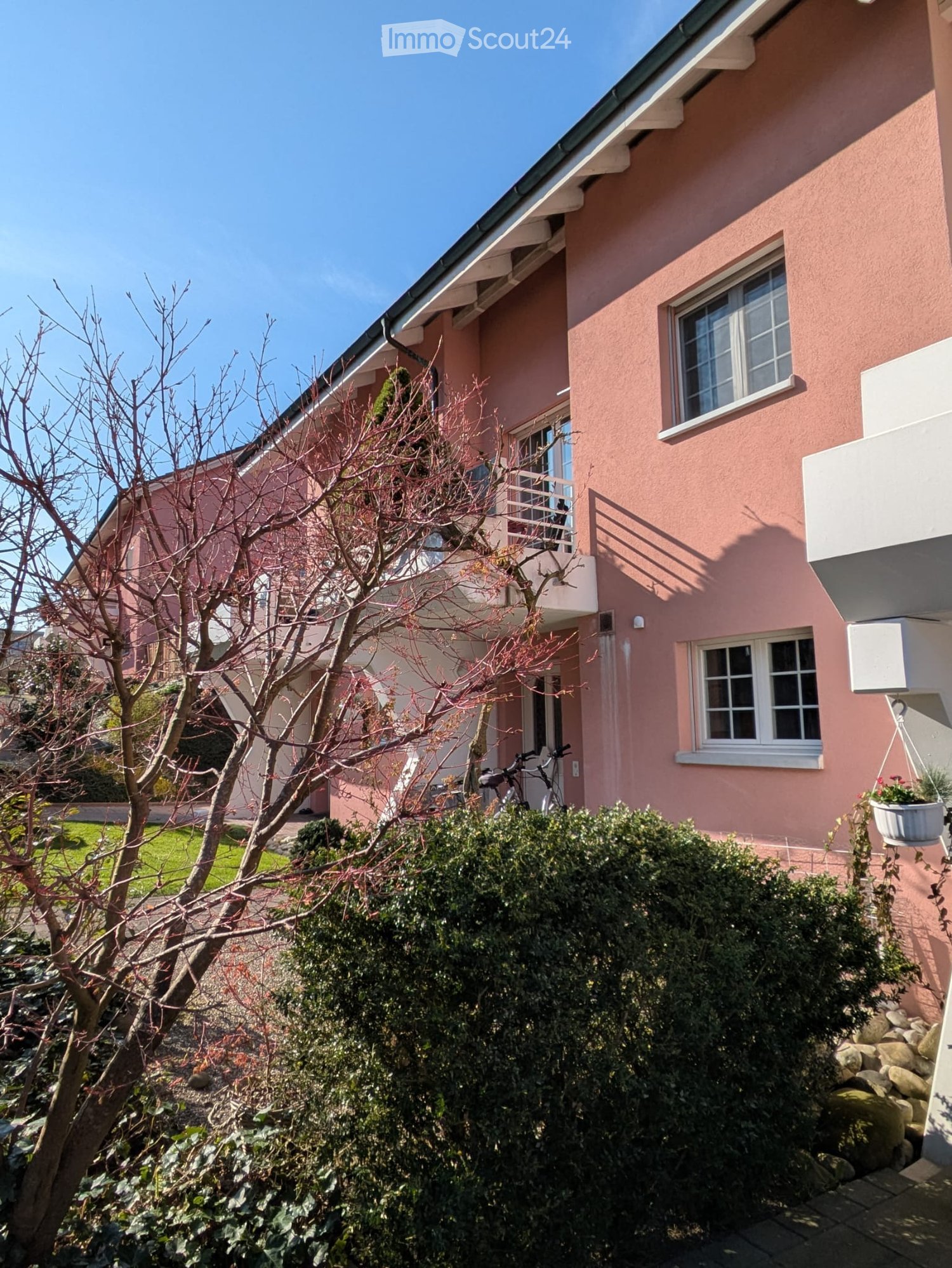 3 story house, pink facade, balcony, plants, bicycles