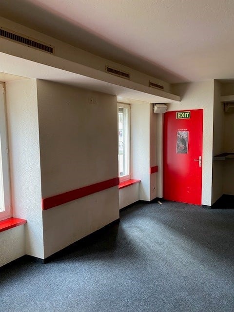 empty room with red door, white walls, gray floor, window, red trims on windows and walls