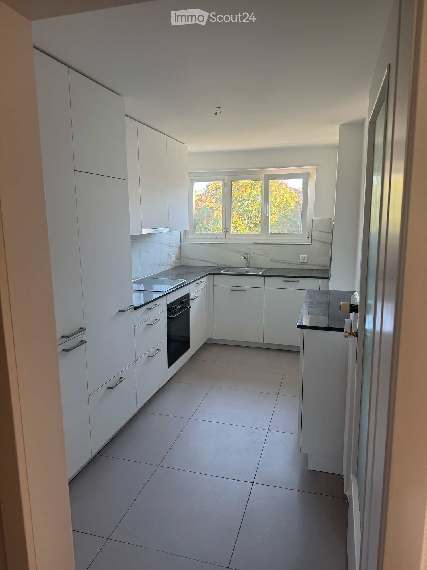 modern kitchen, white cabinets, grey tiled flooring, granite countertops, built-in oven and microwave, double sink, large window