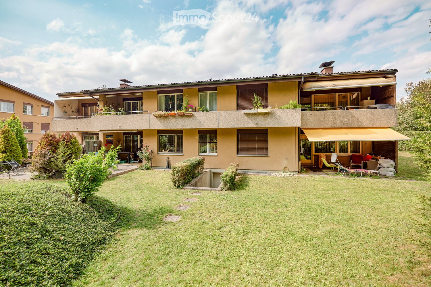 2 story yellow house with several balconies and a garden