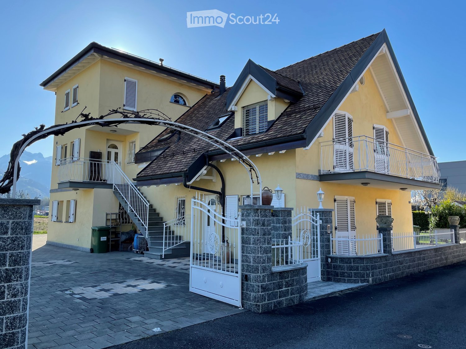 2 story house, yellow walls, brown roof, double gates, balcony, steps