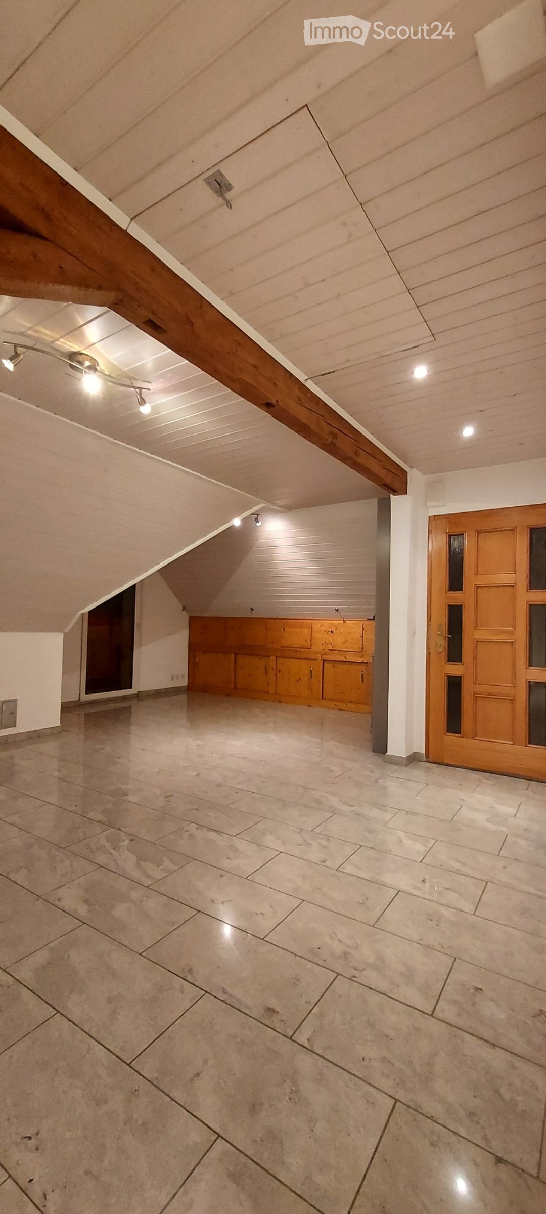 an empty room with wooden beam, tiled floor, wooden closet and wooden door
