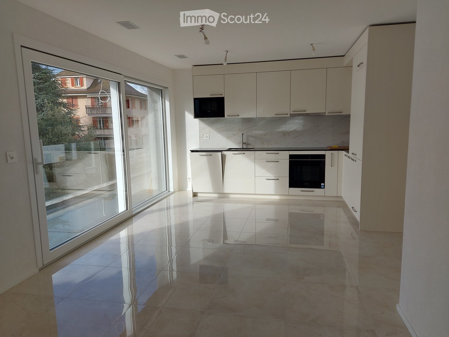 White kitchen cabinets, tiled flooring, marble countertop, large sliding doors, microwave, black oven, double sink.