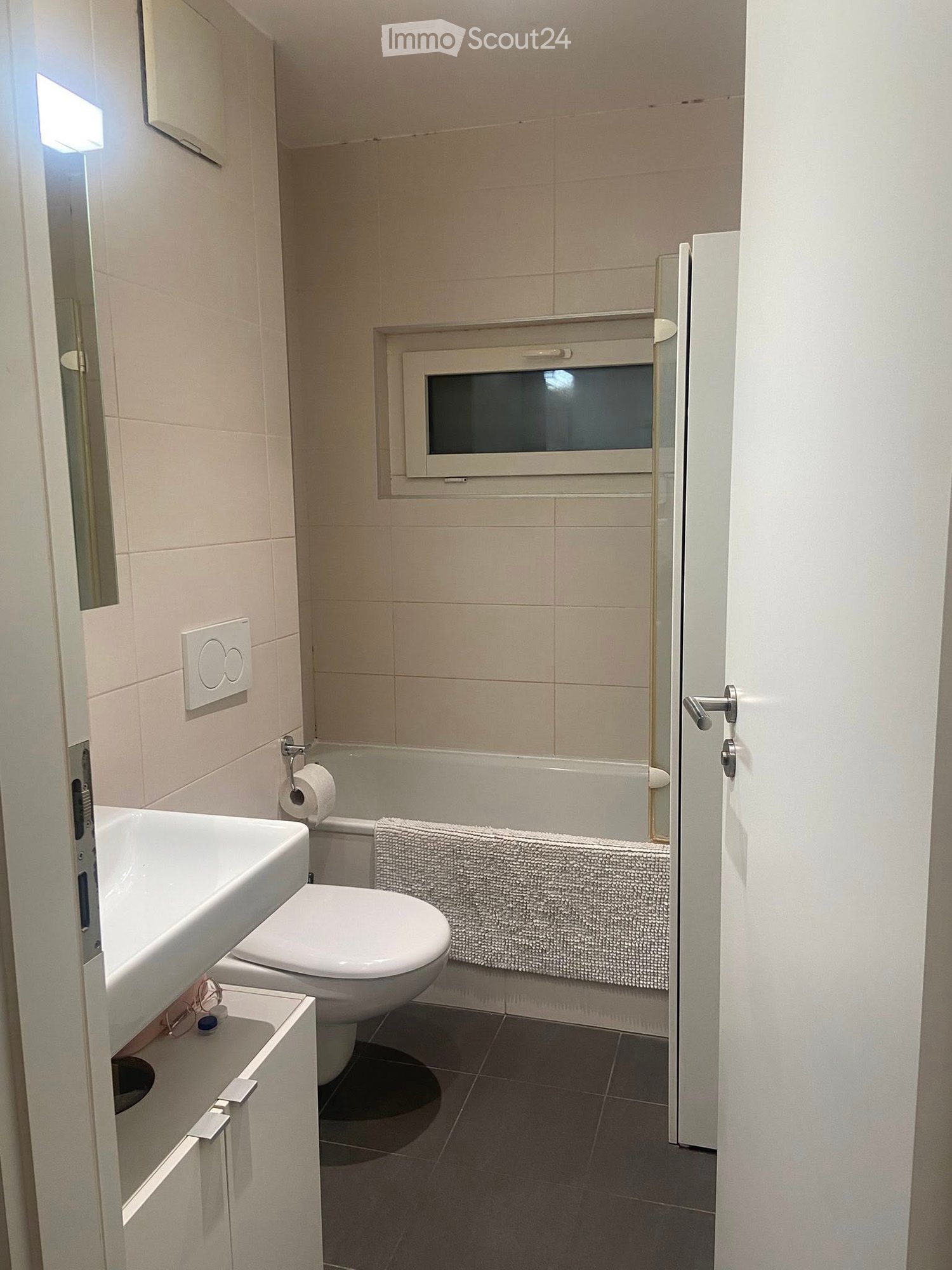 white tiled bathroom, white bathtub, white sink, white toilet, mirror, open doorway