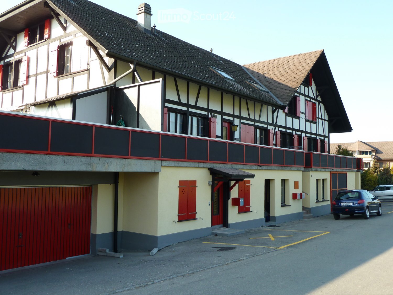 2 story house, red garage door, red shutters, yellow-gray walls, red awning