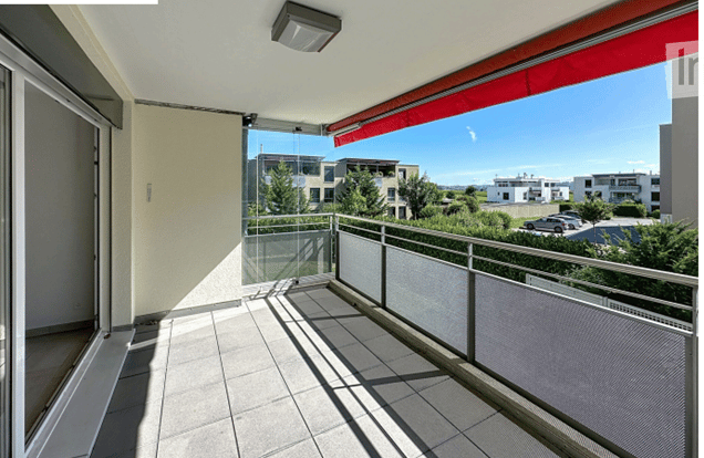 Empty balcony, with glass doors, a metal railing and a red awning