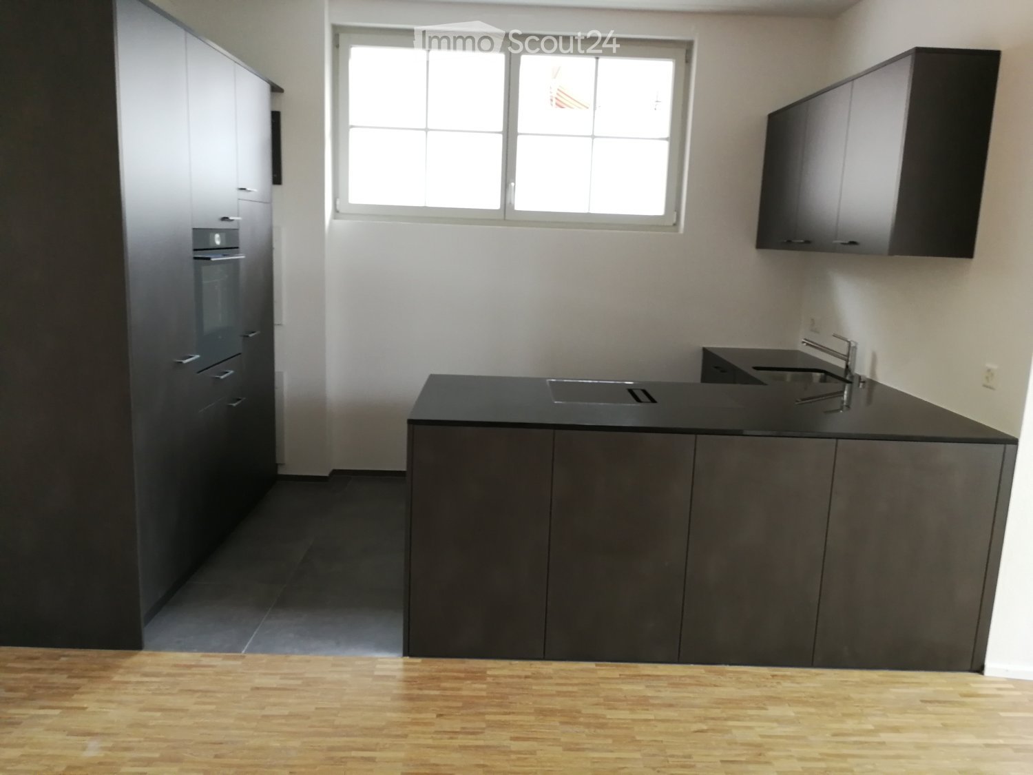 modern kitchen, black countertops, grey cabinets, white walls, window, hardwood floor