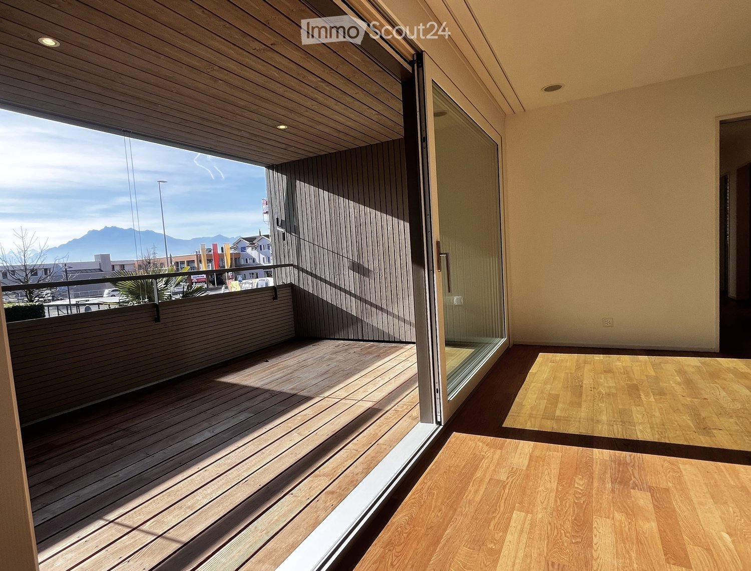 sliding glass door to balcony, wooden floor, view to mountains and town