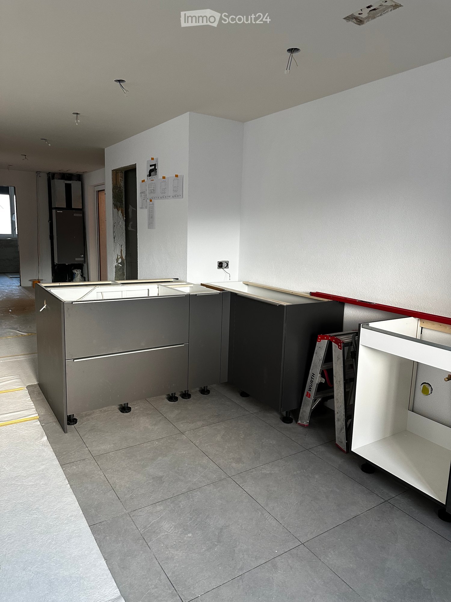 Unfinished kitchen with granite countertop and steel kitchen units, tiled floor, and white walls.