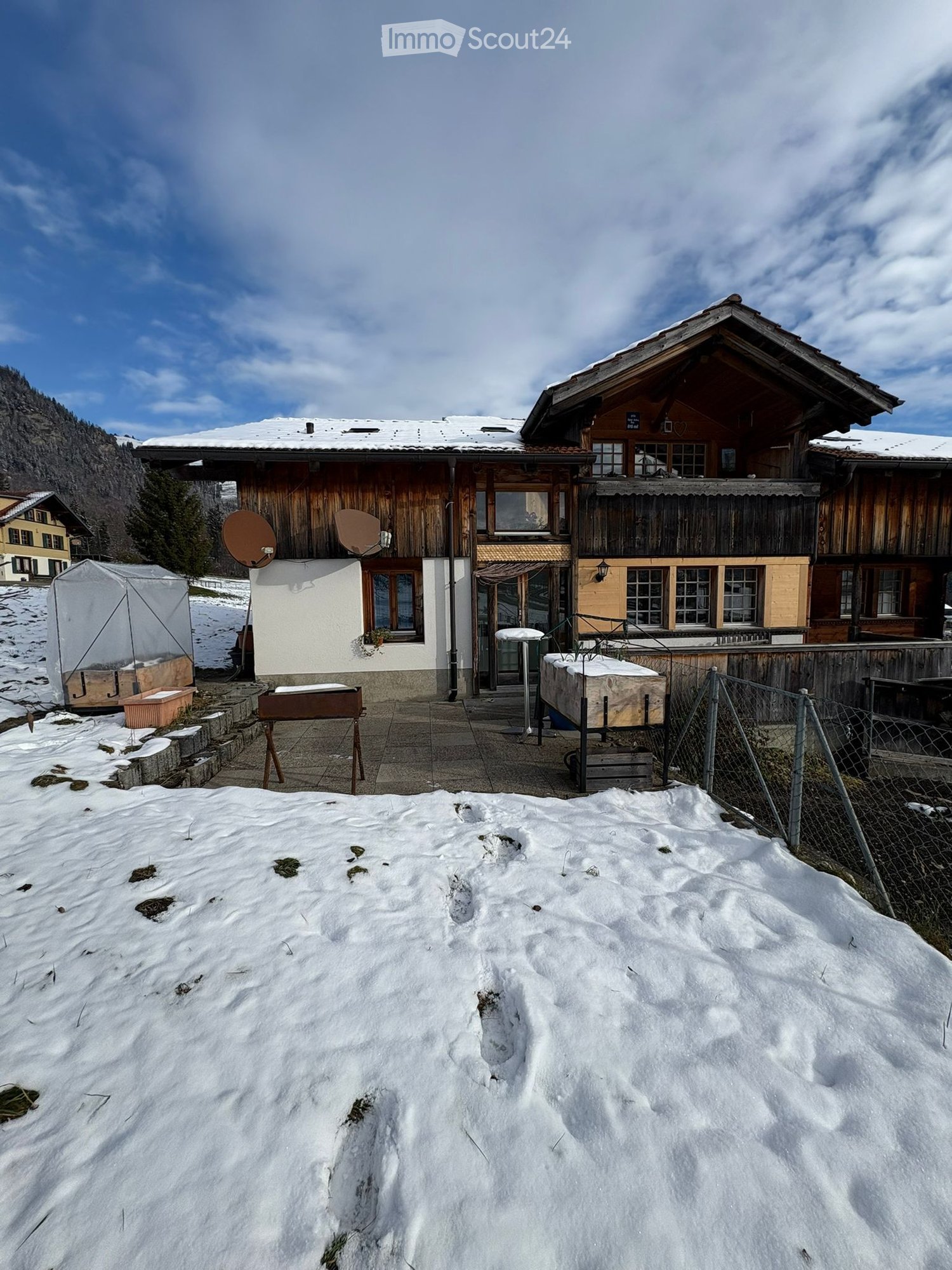 Traditional wooden house, snowy surroundings, satellite dishes, covered porch, fence, outdoor table