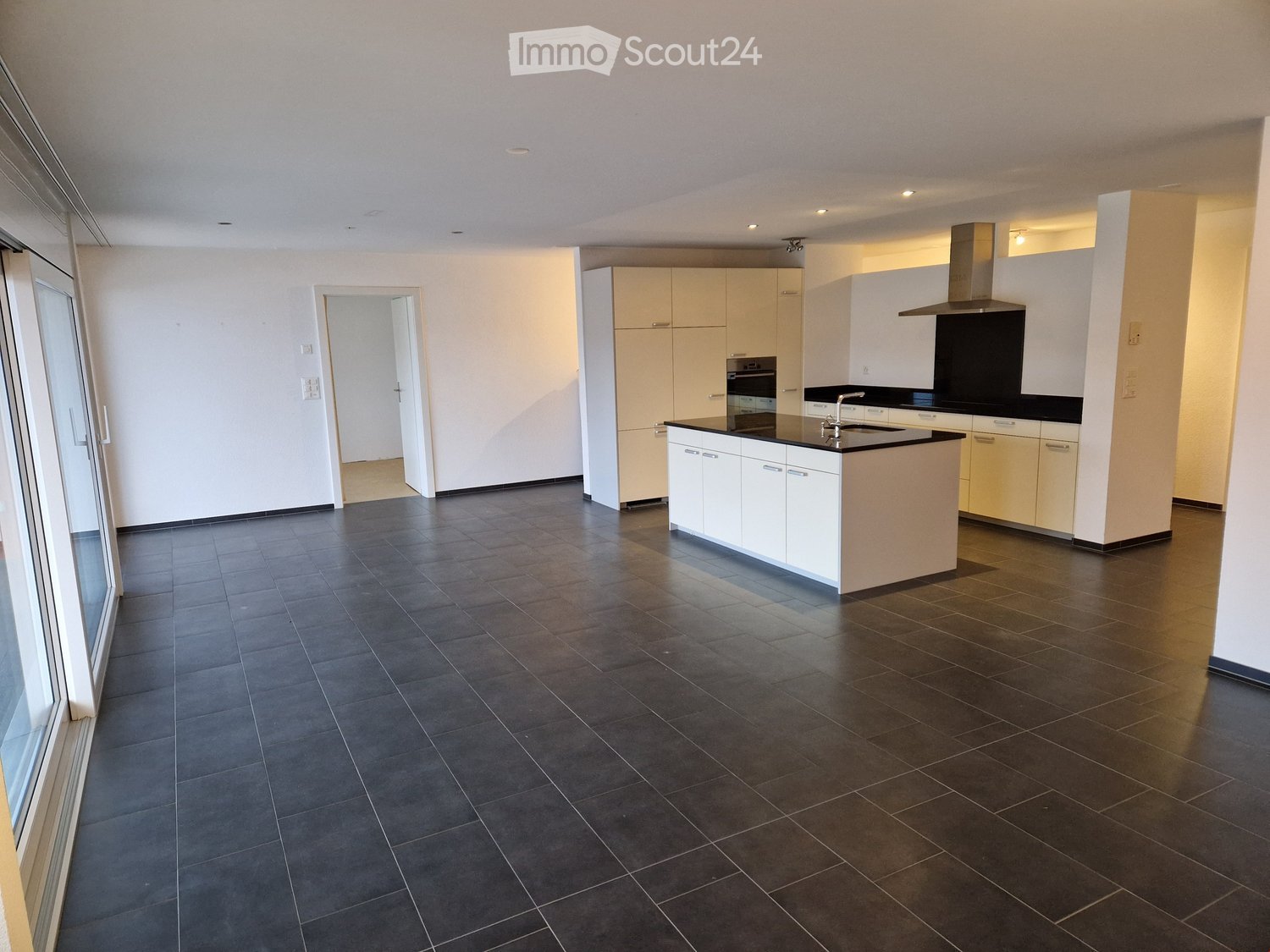 White kitchen with central island, built-in appliances, modern design, and tiled flooring.