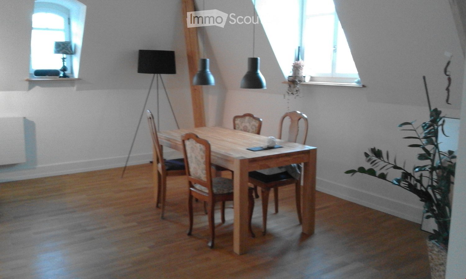 dining room with wooden floor, ceiling beams, windows, table, and chairs