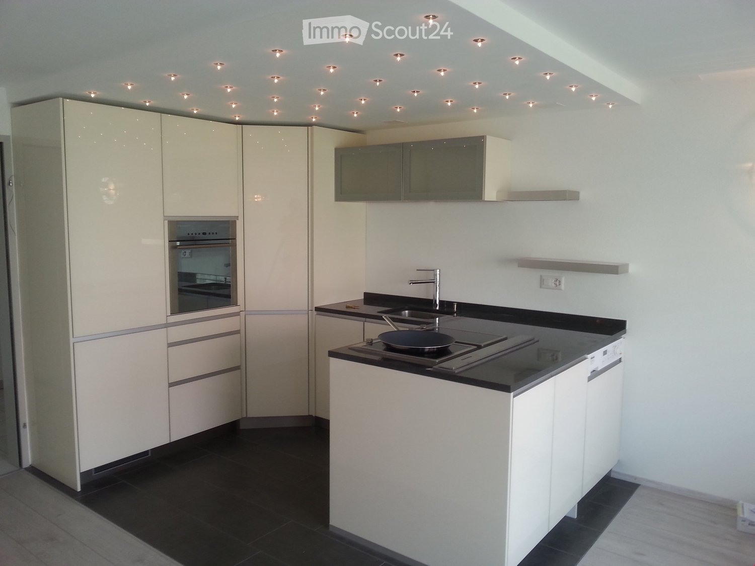 modern kitchen with white cabinets, black countertops, embedded oven and dishwasher, stainless steel sink and faucet, LED ceiling lights