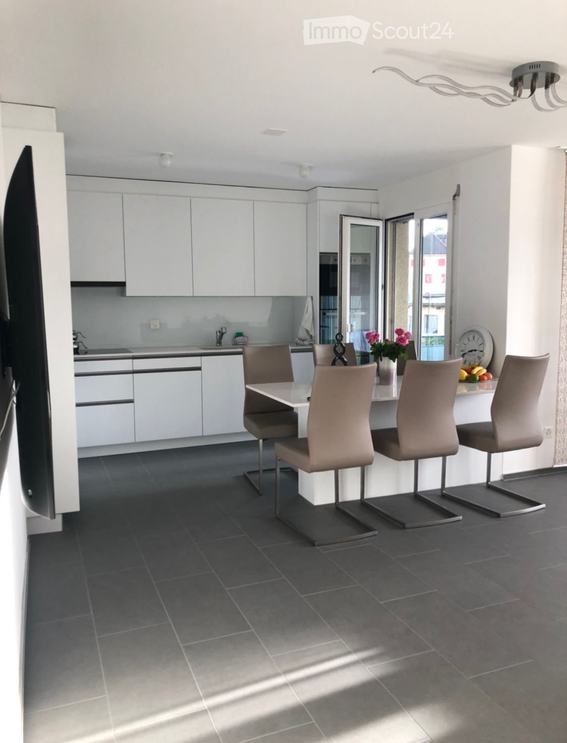 White cabinetry, tiled flooring, table, chairs, countertop, sink, faucet, oven, clock, flowers