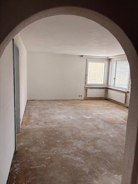 Empty room with white walls and ceiling, empty window sills, floor still unfinished