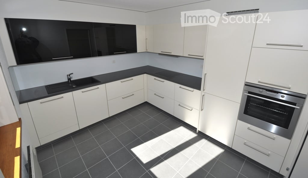 modern kitchen with black countertops, white cabinets, stainless steel appliances, dark tiled floor