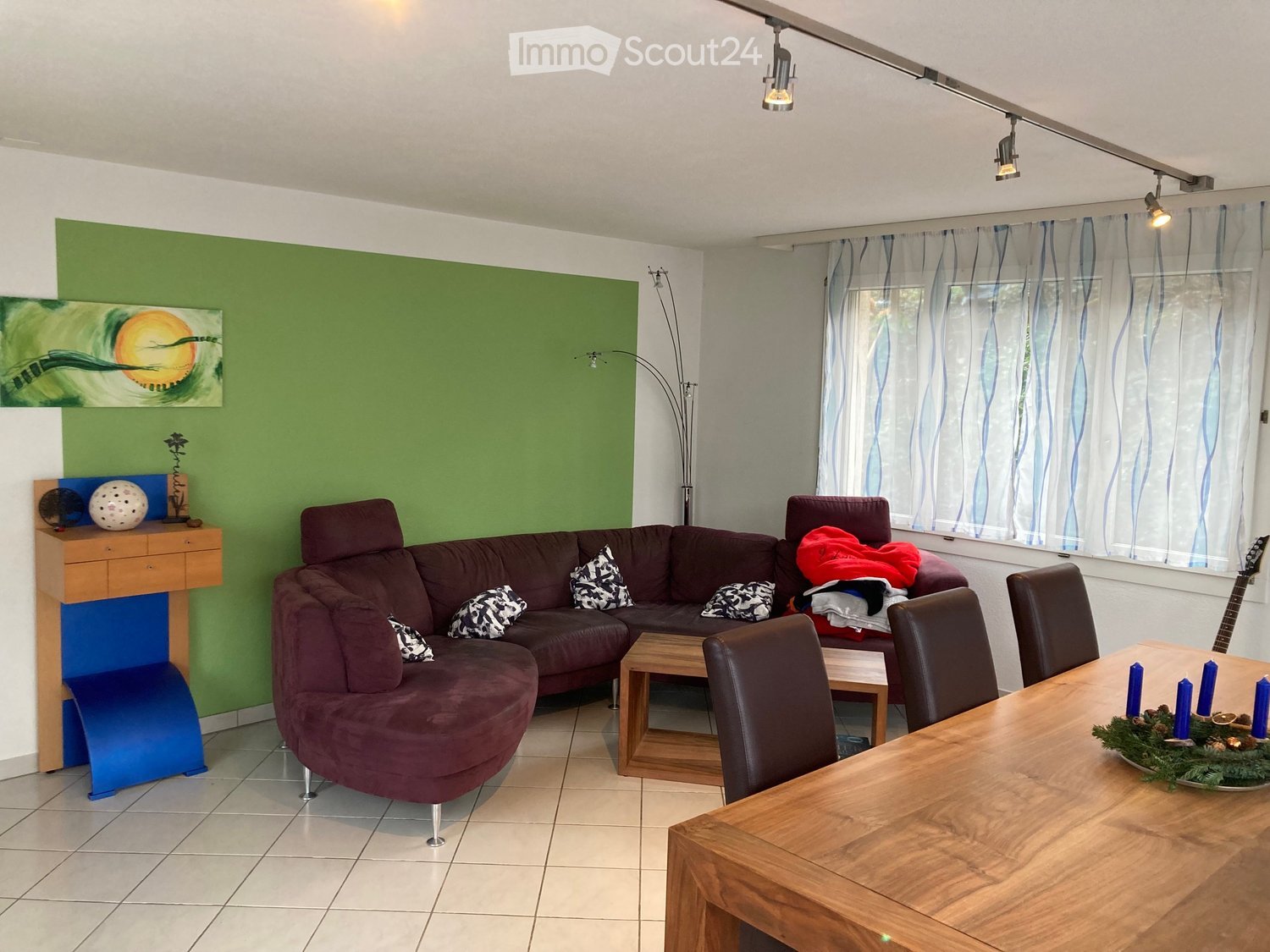 L-shaped sofa, dining table, lamps, blue cushioned bench, wooden side table, decorative balls, window with curtains