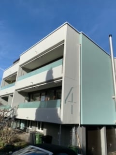 3 story building, white walls, green accents, balconies, number 4 on the side