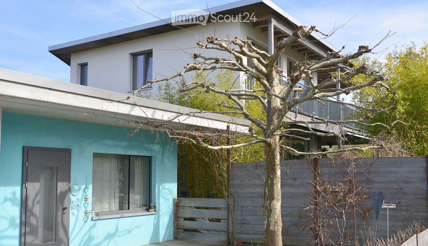 2 story house, blue and white walls, wooden door, windows, balcony on second floor