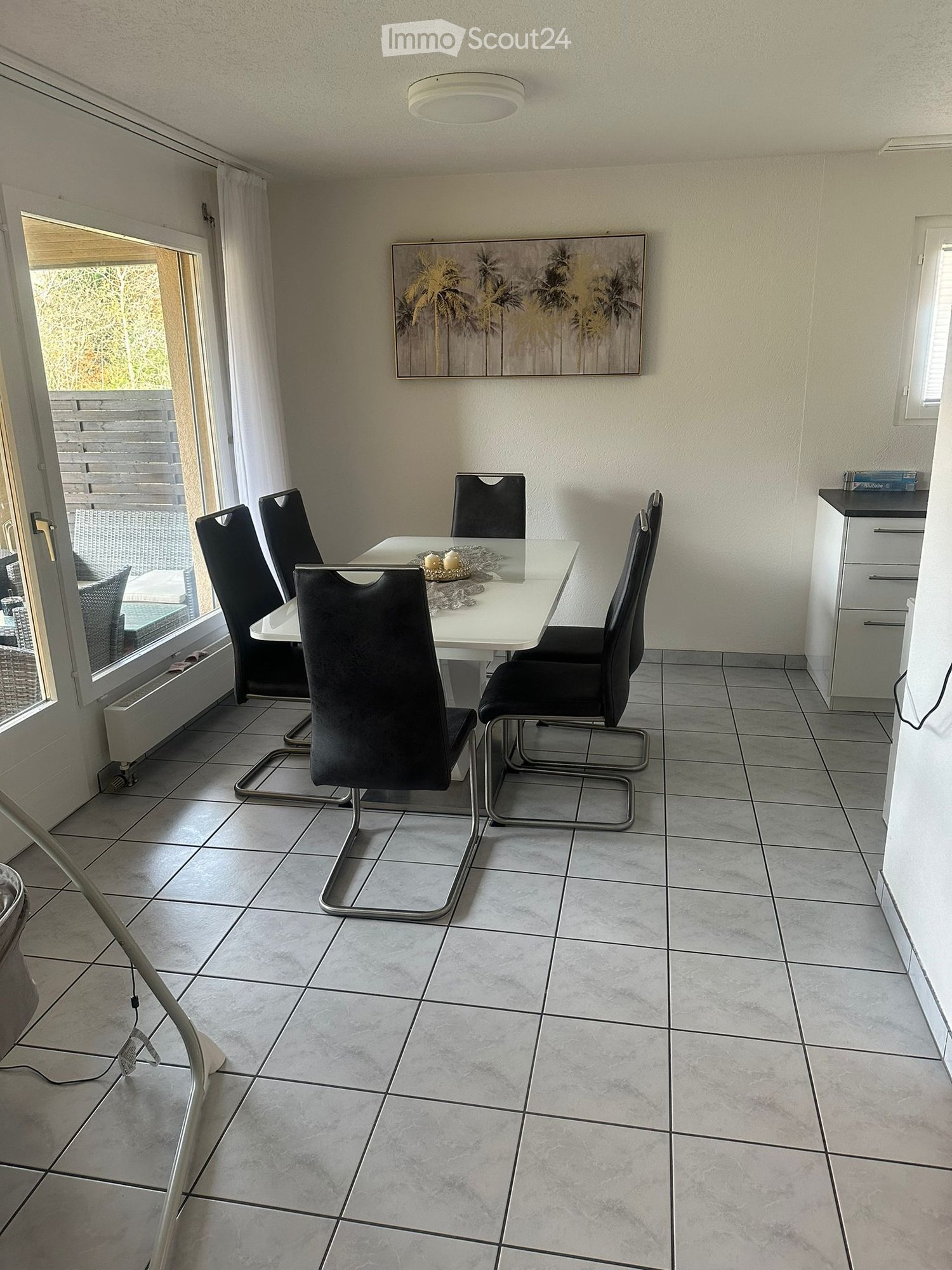 white dining table with 6 chairs, glass door to balcony, white walls, tiled floor