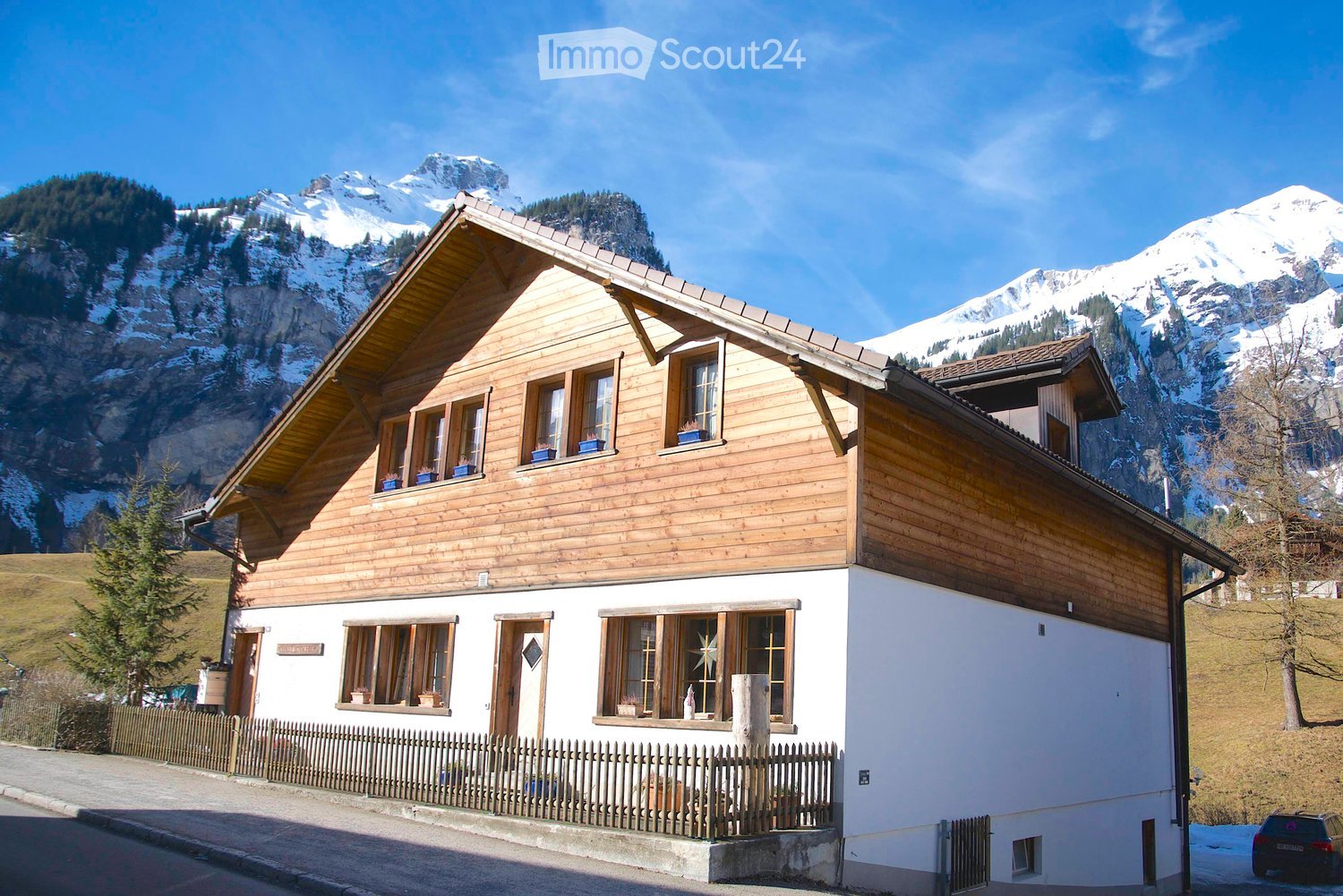 2 story wooden house, brown and white, wooden fences, front garden, snow mountain in background