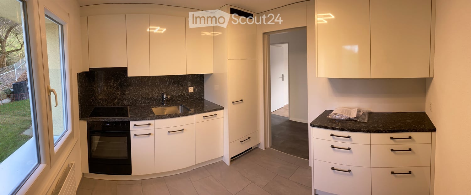 modern kitchen with white cabinets, black granite countertops, stainless steel appliances, open to living area