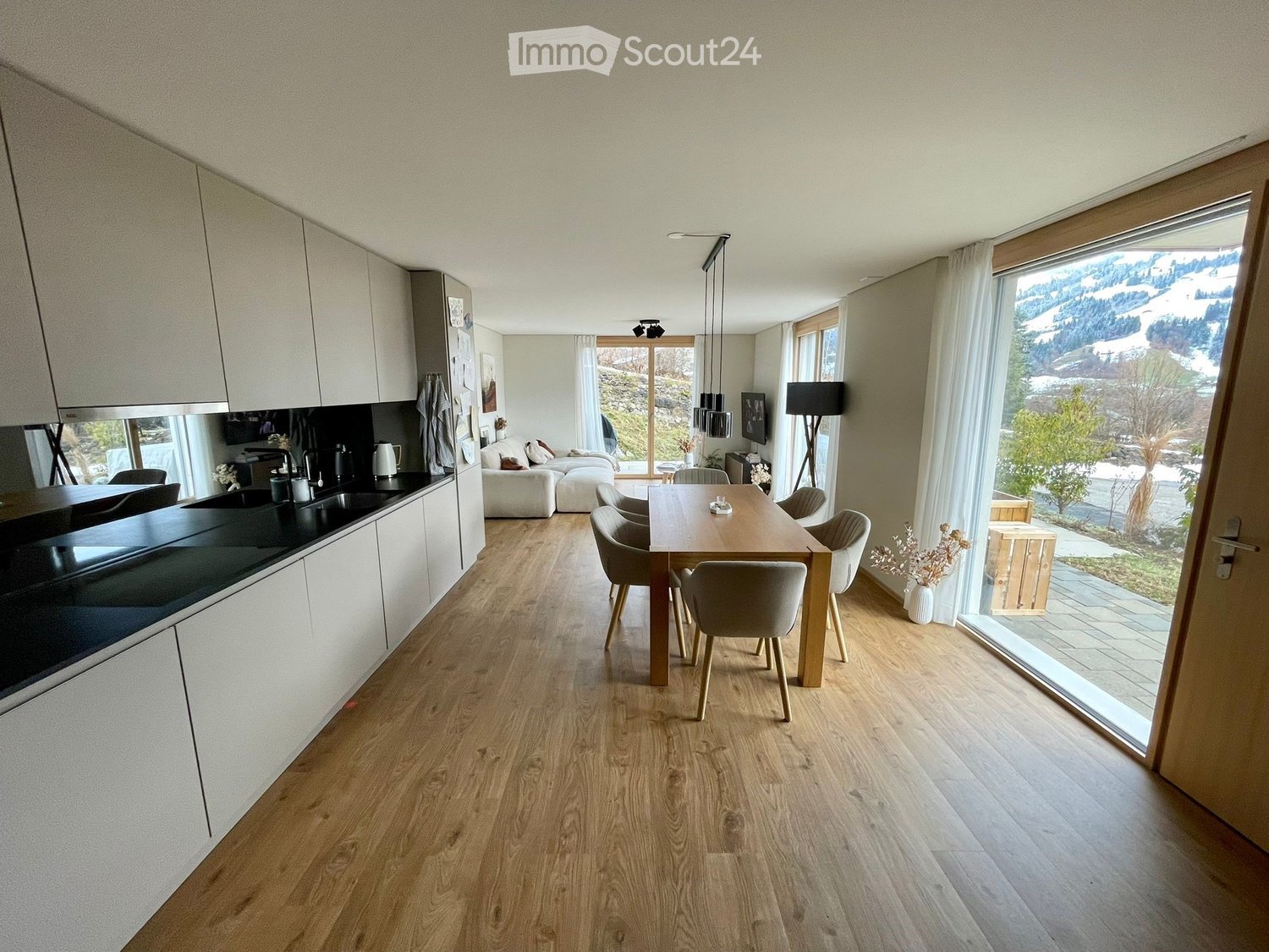 kitchen area with dining table and seating area, open to living room, large windows with view of outside landscape