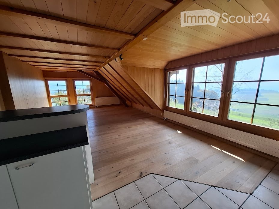 Aerial shot, attic, large windows, wooden flooring, white kitchen area, wooden ceiling