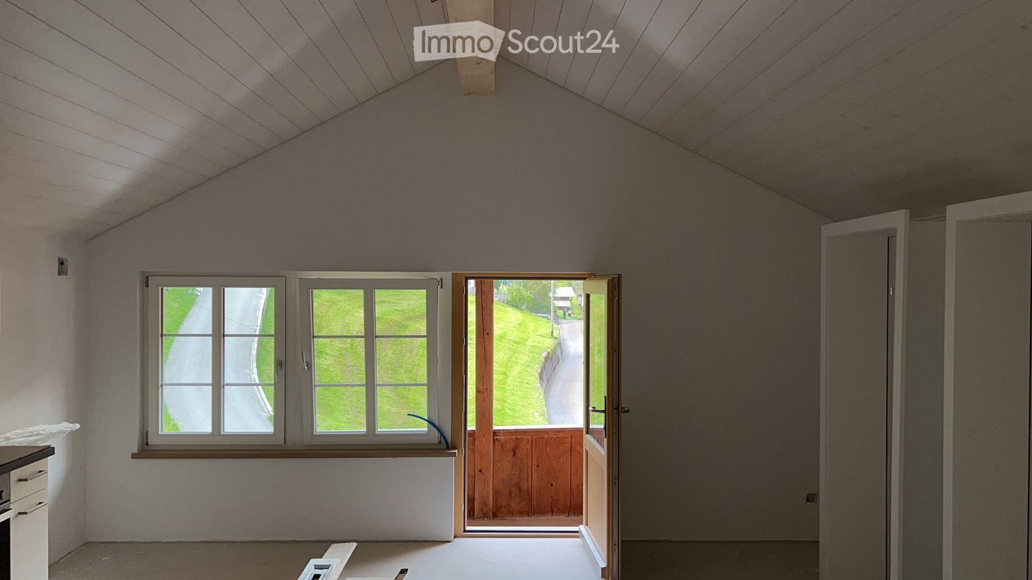 Empty room with windows, wooden entrance, window bench, and white wooden ceiling