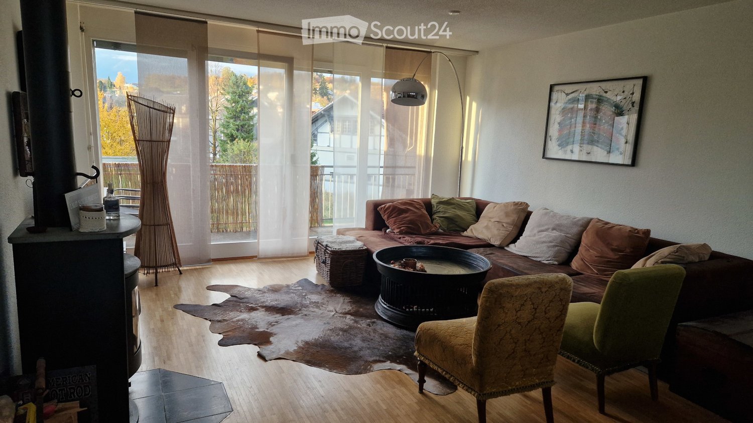 wooden floor, fireplace, couch, armchairs, coffee table, large windows, balcony