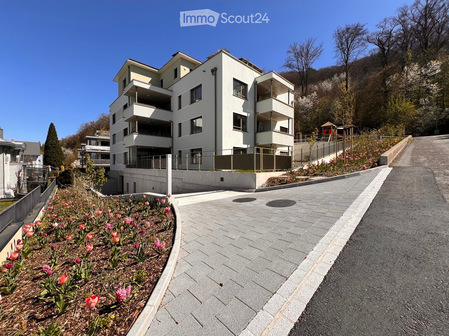 modern apartment building, multiple floors, white exterior, balconies, fenced entrance