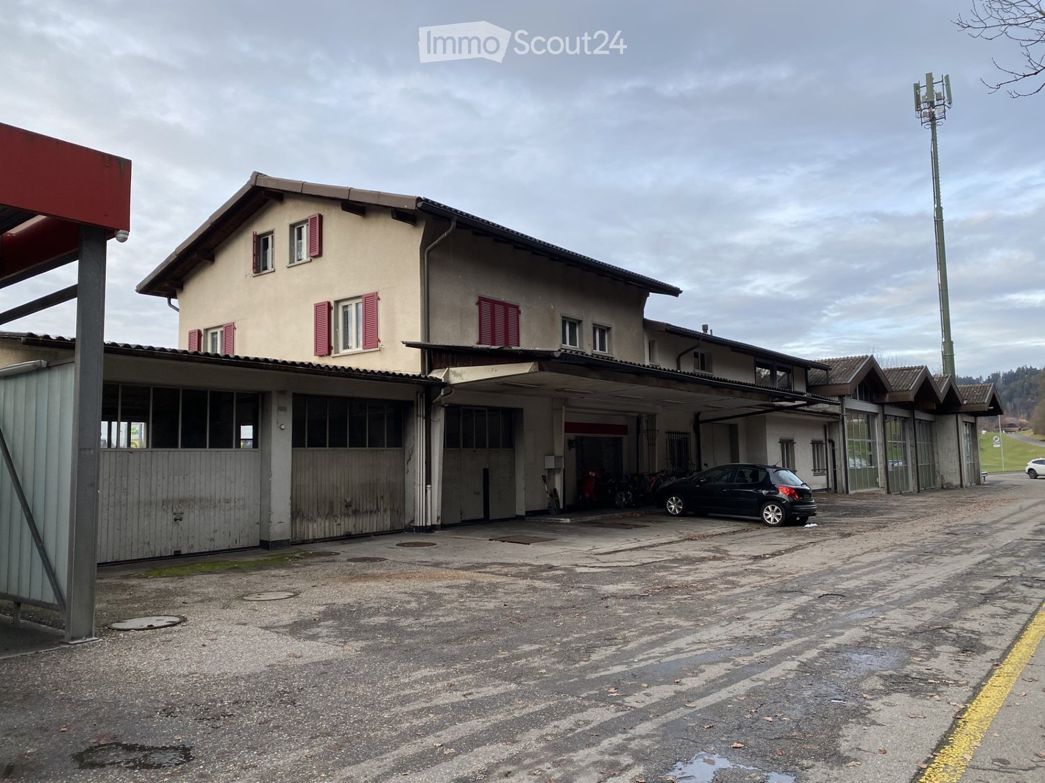 Garage building, beige exterior, multiple garages, parked car in front, gray asphalt ground