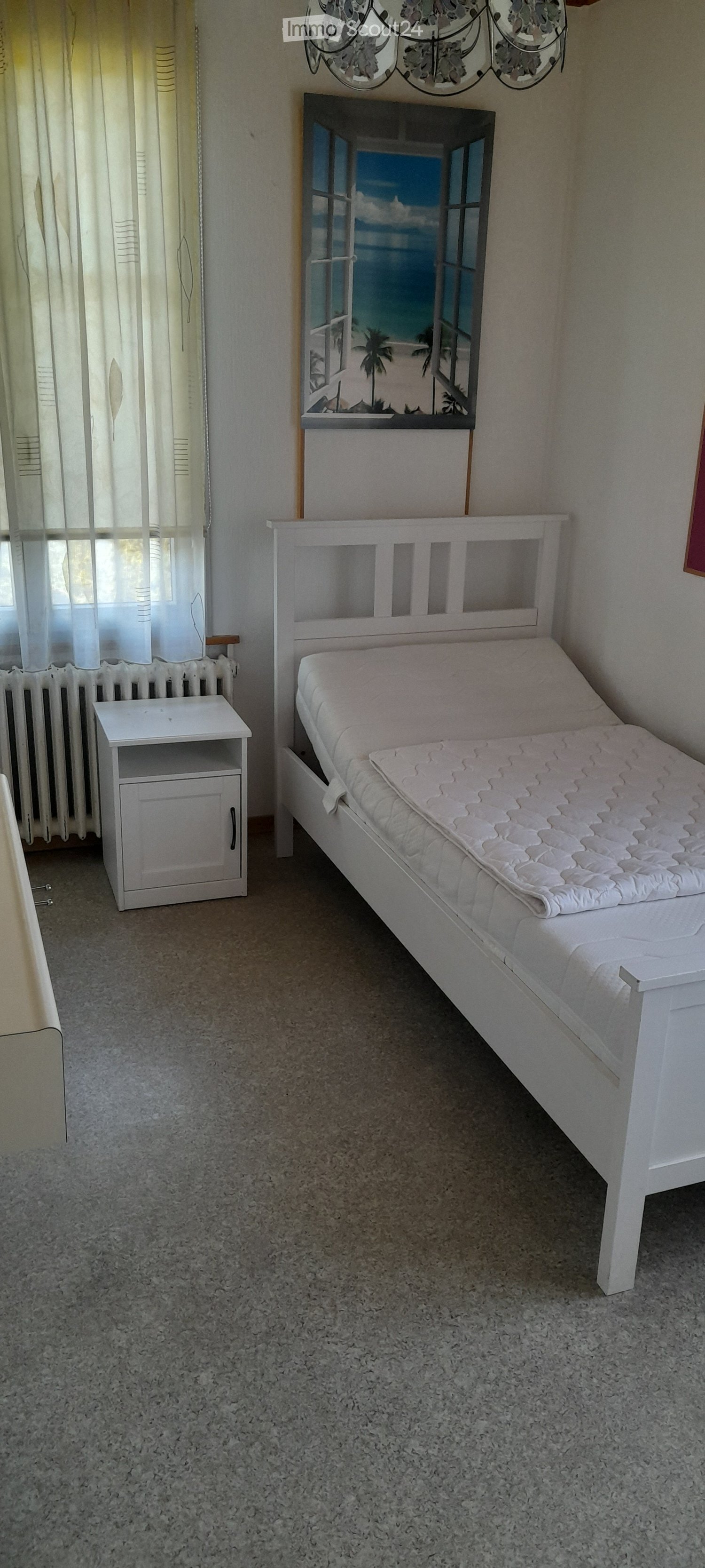 White bed frame, mattress, nightstand, wall decor with tropical beach scene