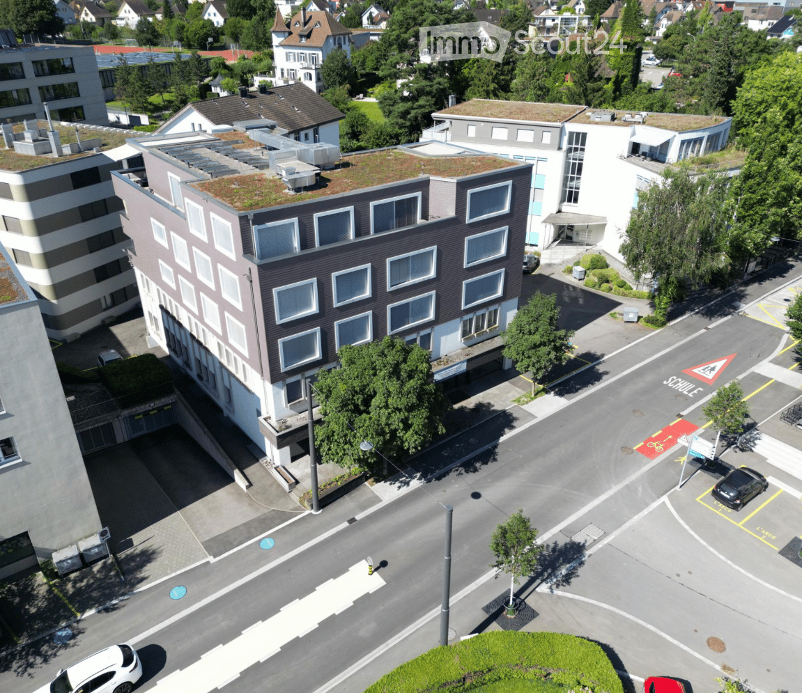 Aerial view of a multi-story building with several windows, a green roof, and an underground parking entrance.