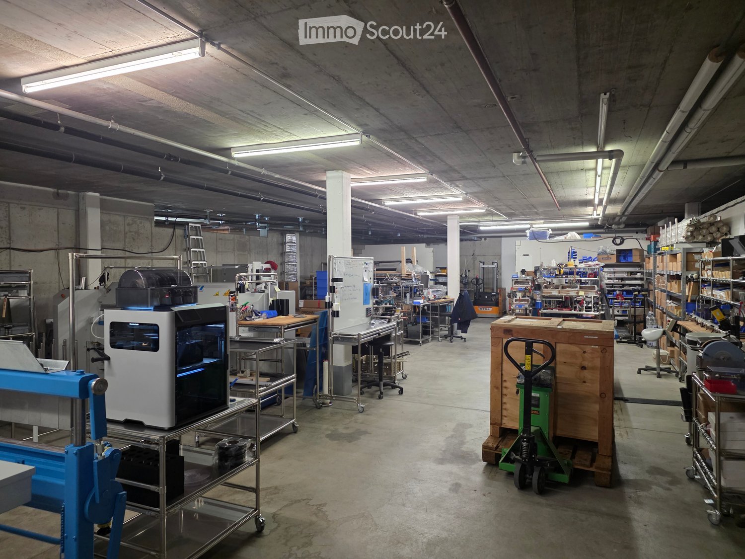 Industrial space with equipment, tables, metal shelves, machines, trolleys, boxes, ladders, pipes
