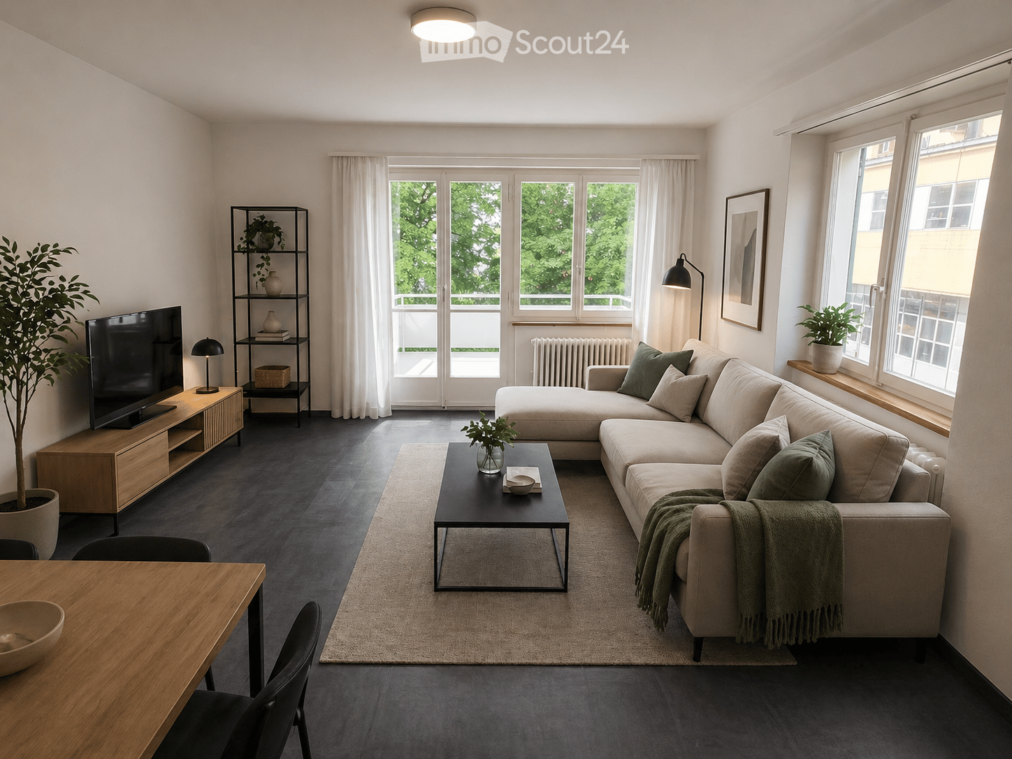 Living Room. Modern living room with a grey sectional sofa, black coffee table, TV on a wooden stand, side table with lamp, and large windows with white curtains.