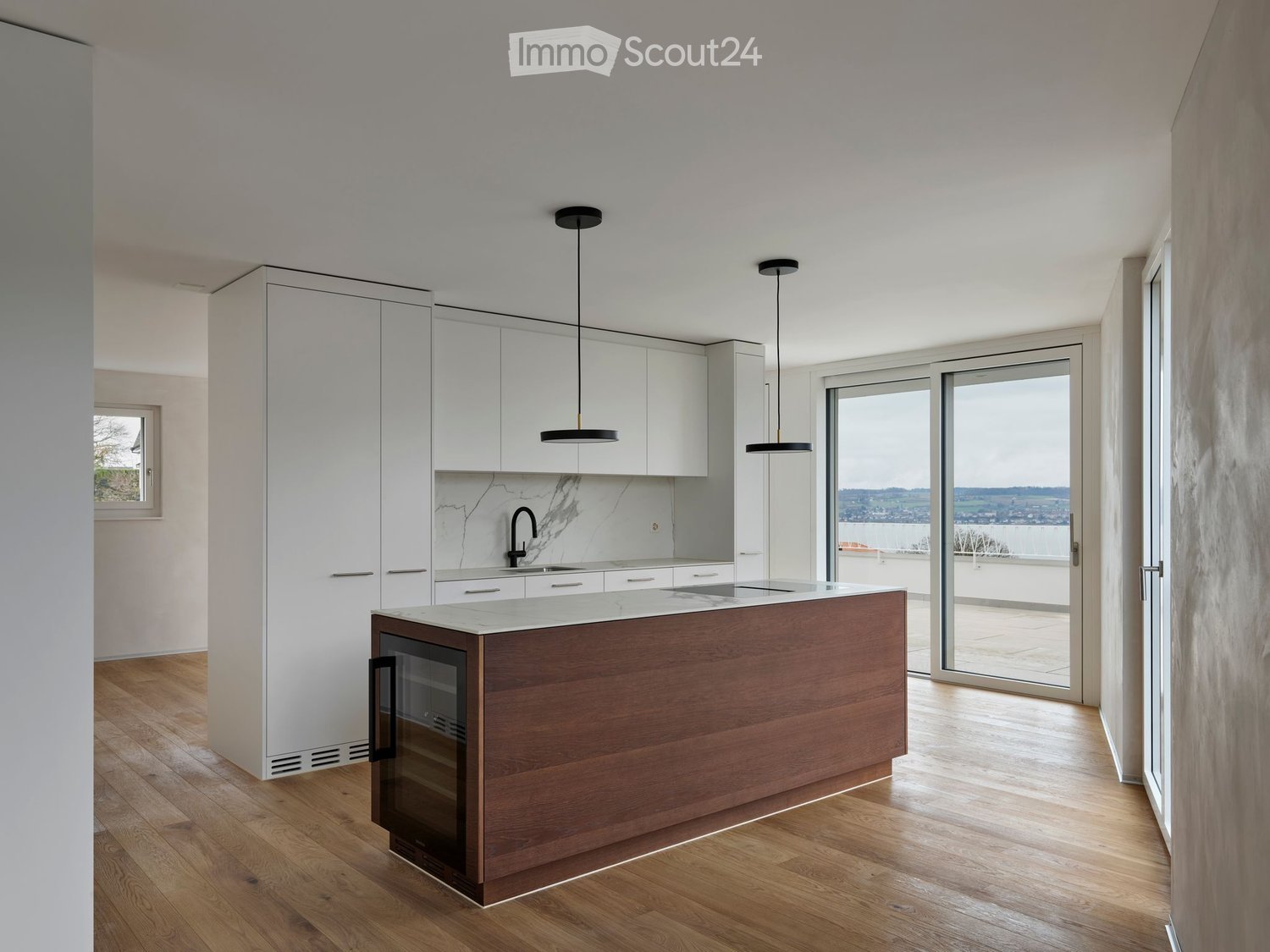 large kitchen island with marble countertop, built-in wine cooler, modern pendant lights, large glass door with sliding glass panels